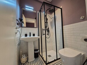 Un bagno moderno con doccia vetrata, lavabo su piedistallo e water.