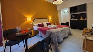 A hotel room with a bed, bedside tables, a dining area, and a kitchenette. - IAIO Testaccio Retrò (Rome)