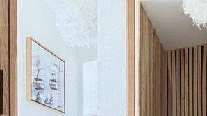A hallway with a wooden floor, a white textured wall, and a framed picture of a mountain landscape. - Appt Prestige - accès facile piste - Thalasso (Saint-Lary-Soulan)