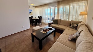 A living room with a sofa, a coffee table, and a dining area with chairs and a table. - Apartment Val (Crikvenica)