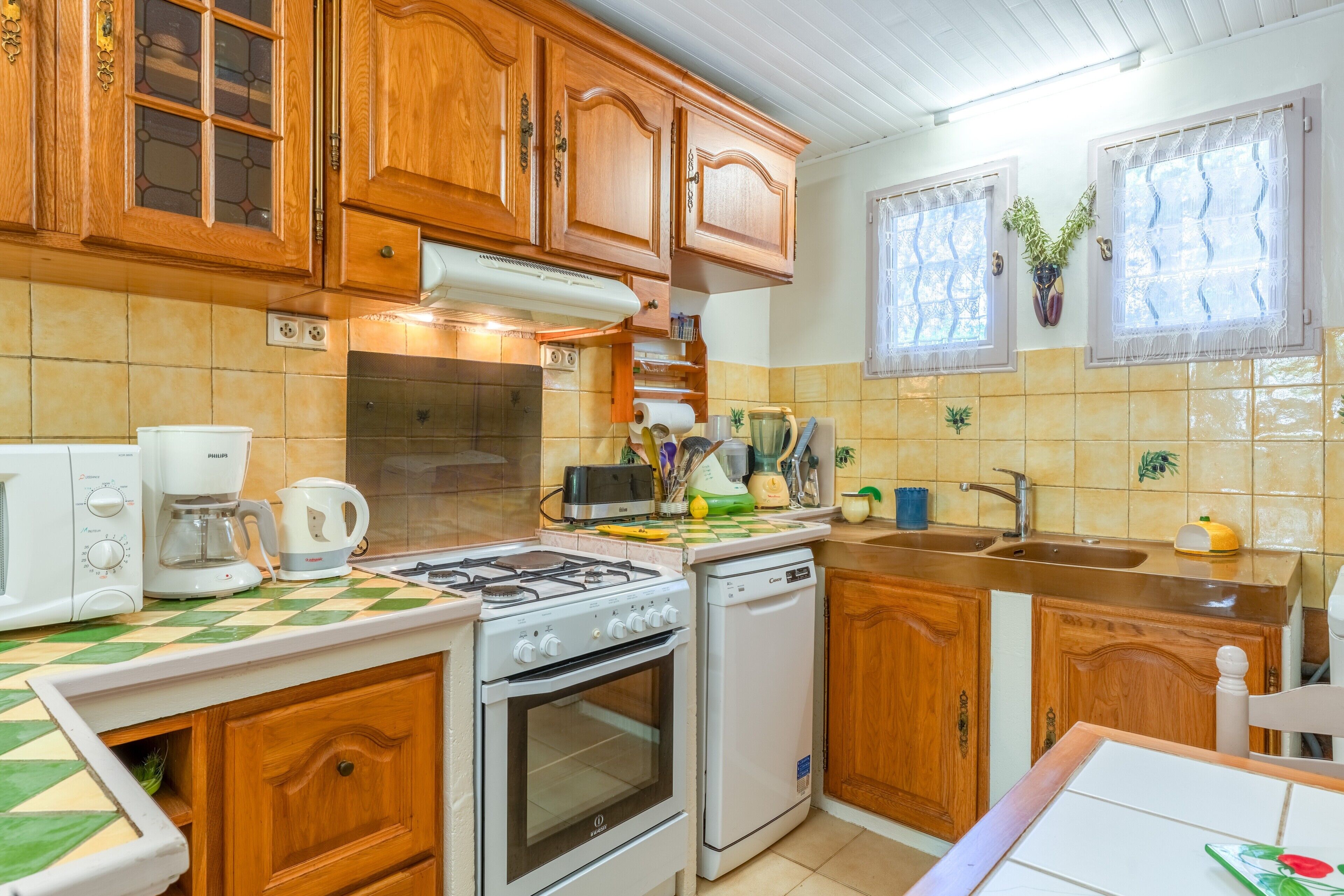 Una cocina con armarios de madera, estufa a gas, lavavajillas y microondas.