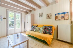 A room with a sofa, a table, a cabinet, a bulletin board, and a radiator. - Studio 'Le Petit Mas Des Pins' with Shared Pool, Wi-Fi and Air Conditioning (Eygalières)