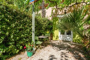 A garden with a table and chairs, a potted plant, and a green door. - Studio 'Le Petit Mas Des Pins' with Shared Pool, Wi-Fi and Air Conditioning (Eygalières)