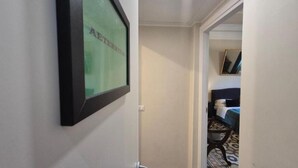 A hallway with a framed picture on the wall, a door leading to a room with a bed and patterned carpet. - HEBE Eternity Rooms (Rome)