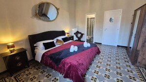A hotel room with a large bed, a round mirror, a nightstand, and a patterned floor. - HEBE Eternity Rooms (Rome)