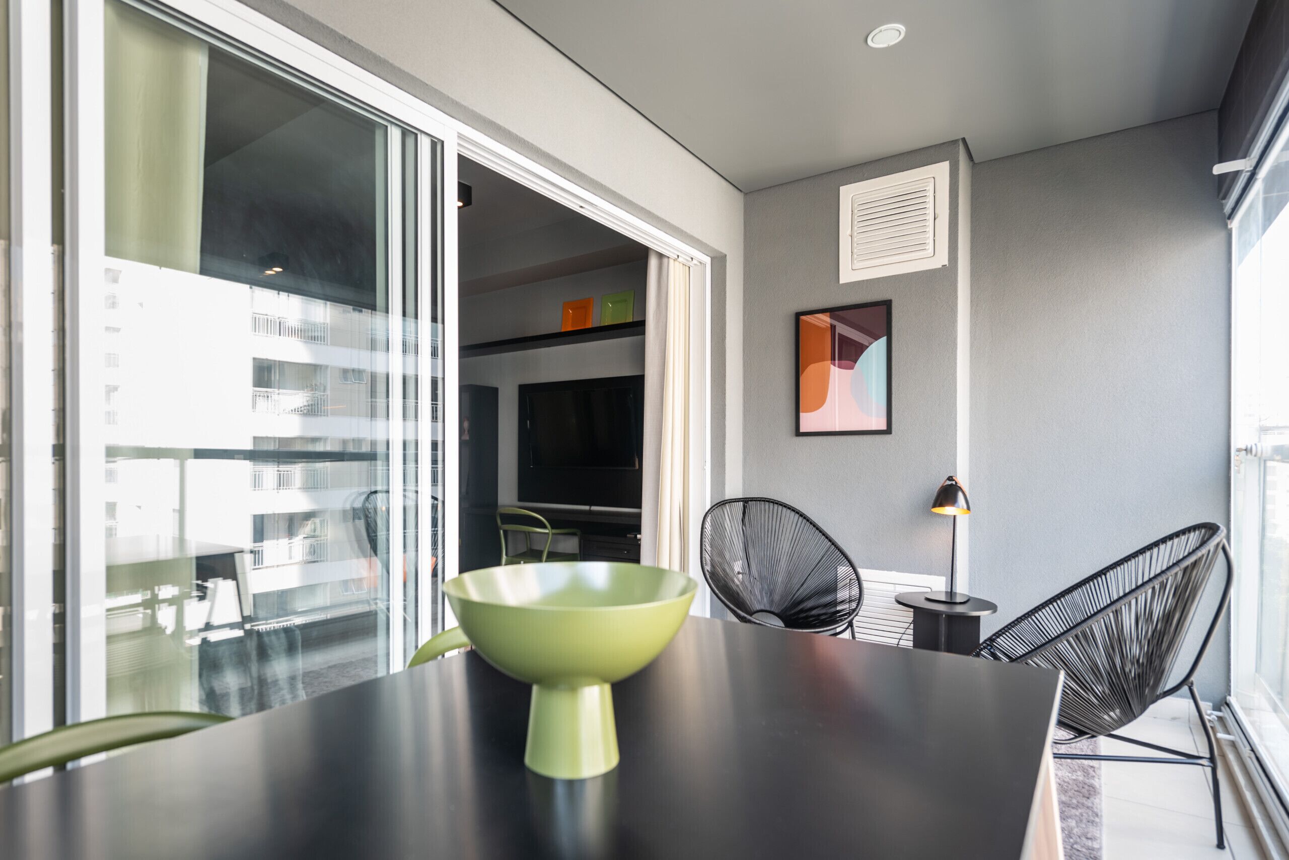 A modern dining area with a black table, a green bowl, and two black chairs.