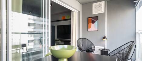 A modern dining area with a black table, a green bowl, and two black chairs.