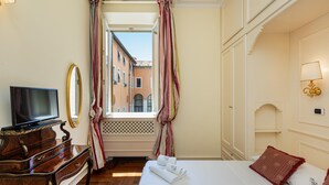 A hotel room with a bed, a television, a desk, and a window with curtains.