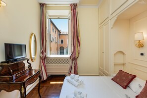 Una habitación de hotel con cama, televisión, escritorio y ventana con cortinas.