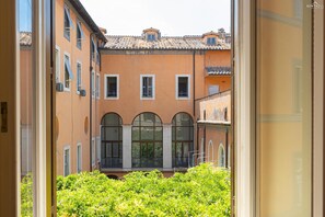 Un patio con un edificio que tiene ventanas de arco y un balcón.