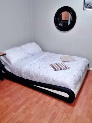 A bed with a white duvet, a striped pillow, and a black headboard.