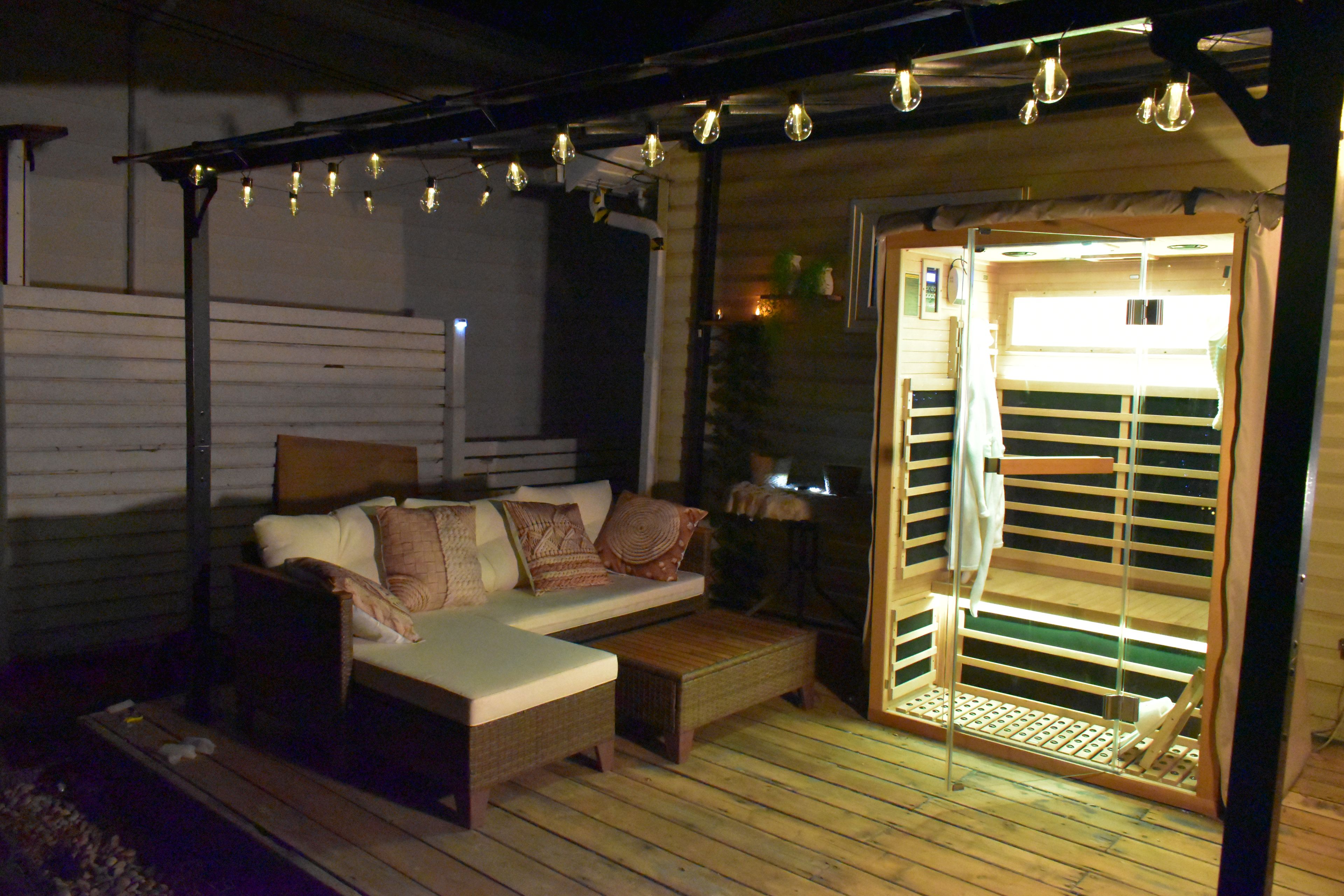 A cozy room with a wooden floor, a sofa with cushions, and a sliding door leading to a balcony.