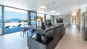 Een moderne keuken met een groot kookeiland, inbouwapparatuur en uitzicht op de omgeving.