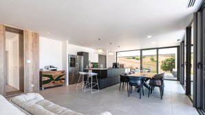 Een moderne keuken met een eethoek, grote ramen en uitzicht op de omgeving.