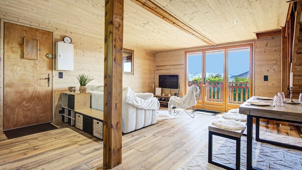 Ein Holzblockhaus-Innenraum mit einer Couch, einem Fernseher und einem Essbereich.