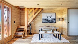 Ein Holzinnenraum mit einer Treppe, einem Esstisch mit Bänken und einem gerahmten Bild an der Wand.