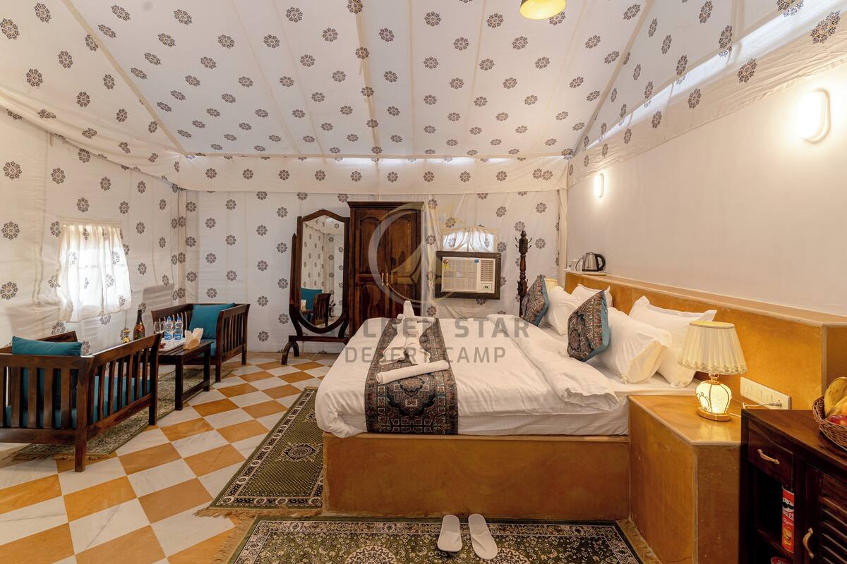 Een slaapkamer met een kamerbreed schaakbordvloerkleed, een bed met een beddengoed met een patroon, een houten nachtkastje, een lamp en een spiegel.