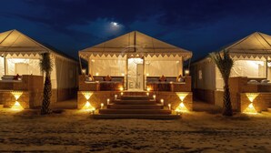 Um resort no deserto com três tendas, cada uma com varanda e escadaria que dá acesso à entrada.