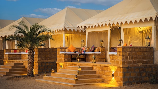 Um resort no deserto com várias tendas, cada uma com fachada de pedra e uma pequena varanda.