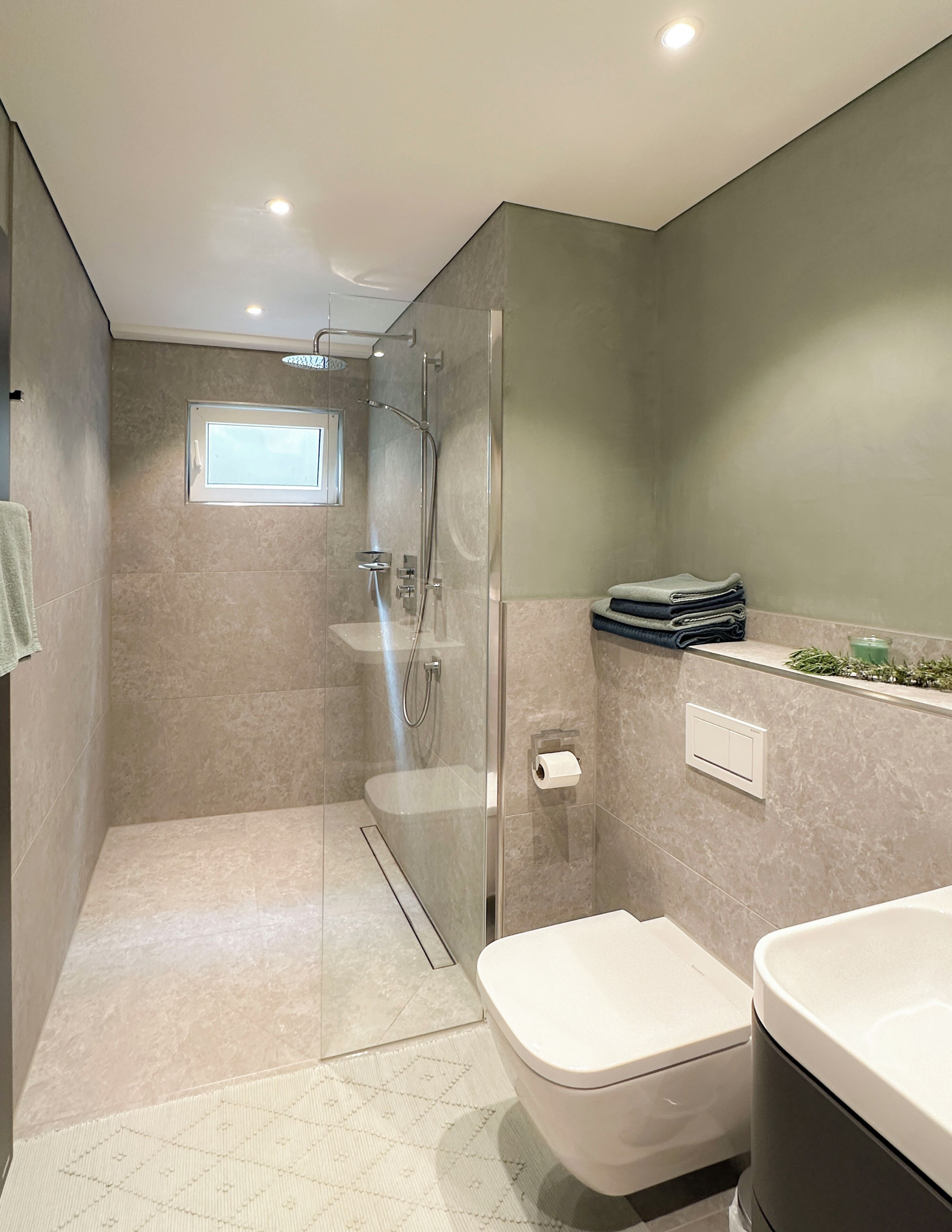 A modern bathroom with a glass-enclosed shower, a toilet, and a sink.
