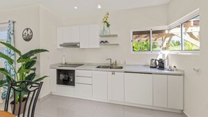 Una cocina moderna con armarios blancos, horno empotrado y ventana con vistas a la vegetación.