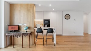 Una cocina moderna con armarios blancos, un microondas negro y una pared de acento de madera.