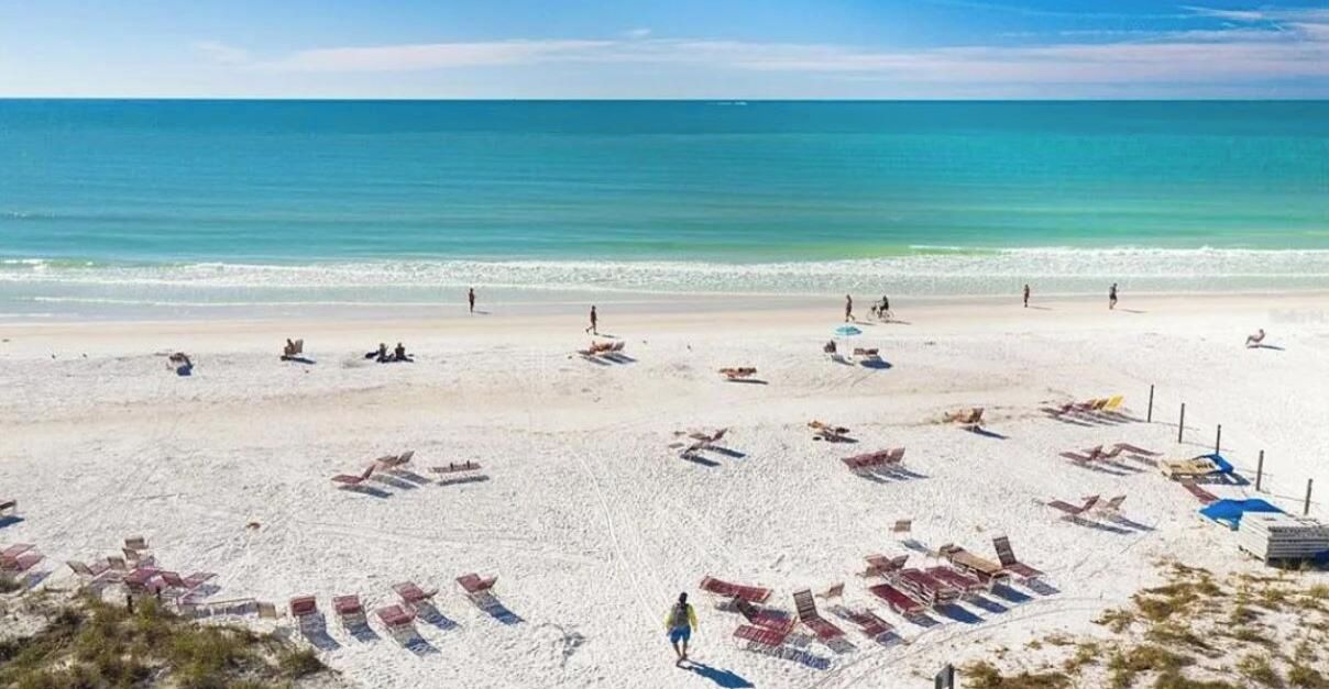 A beach with sun loungers and umbrellas, a sandy shore, and the ocean in the background.