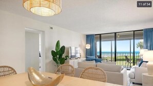 Un salon moderne avec un coin repas, une grande fenêtre offrant une belle vue et un balcon.
