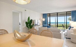 A modern living room with a dining area, a large window with a view, and a balcony.