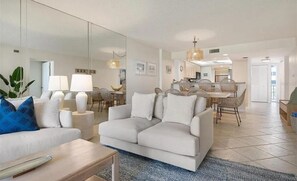 A modern living room with a sofa, a coffee table, and a dining area with a table and chairs.