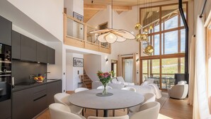 A modern kitchen with dark cabinets, a central island, and a dining area with a round table and chairs.