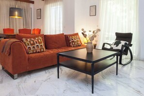 Una sala de estar con un sofá, una mesa de centro, una silla y una lámpara.