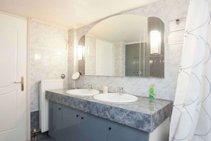 Un bagno con due lavandini, uno specchio grande e un portasciugamani.