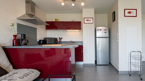 Eine kleine Küche mit einem roten Sofa, einer Kaffeemaschine, einer Mikrowelle und einem Kühlschrank.