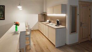 Moderni keittiö, jossa on valkoinen työtaso, puiset kaapit ja yksi tuoli.