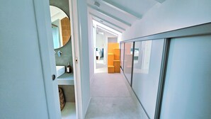 A hallway with a bathroom on the left, a wardrobe on the right, and a bed in the background. - The Attic Room on Niella Street, in the city center and near the sea (Savona)