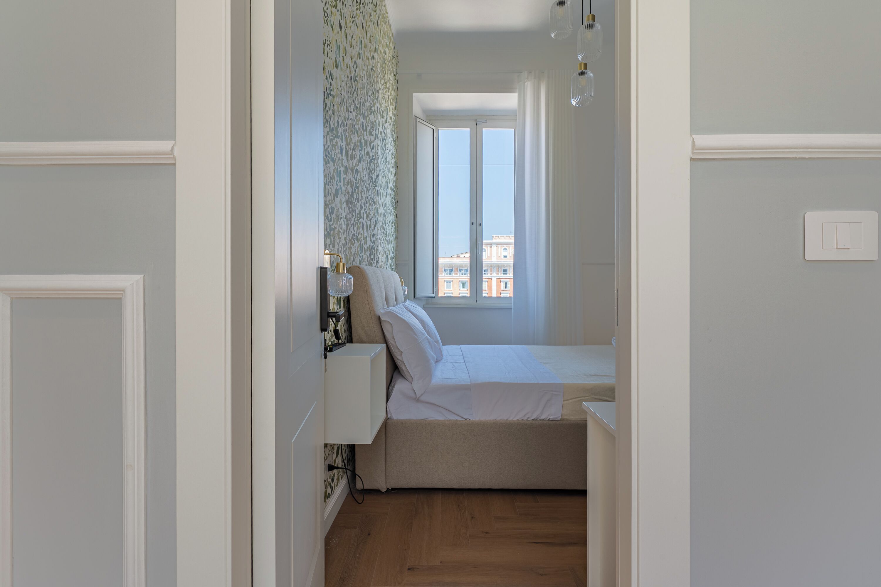 A narrow room with a bed, a window, and a door.