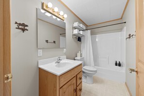 A bathroom with a vanity, sink, mirror, and a shower area.