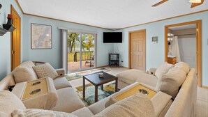 A spacious living room with a large sofa, a coffee table, and a flat-screen TV mounted on the wall. -  Scenic riverfront cottage with boat landing and docks. (Nekoosa)