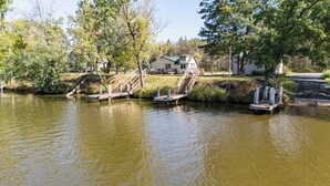 A lakeside property with a dock, a house, and a staircase leading to a deck. -  Scenic riverfront cottage with boat landing and docks. (Nekoosa)