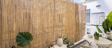 A bamboo wall with potted plants and a wicker basket.