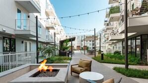 A modern outdoor patio with a fire feature, seating, and a pool area. - Brand New luxury 1 bedroom (Austin)