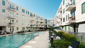 A modern hotel with a swimming pool, outdoor seating, and balconies. - Poolside Luxury | 1BR w/ Private Patio (Austin)