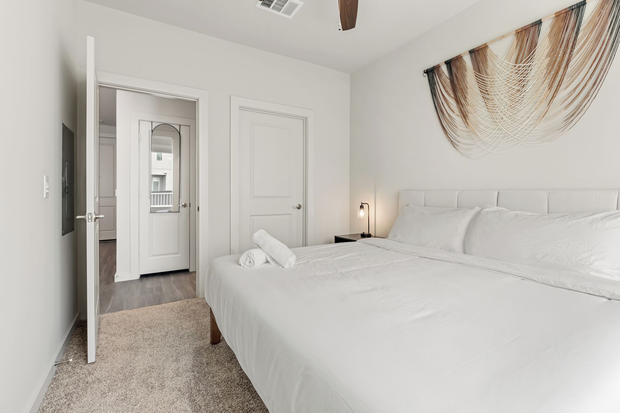 Ein Hotelzimmer mit einem großen Bett, einem an der Wand befestigten Fernseher und einer Tür zu einem Balkon.