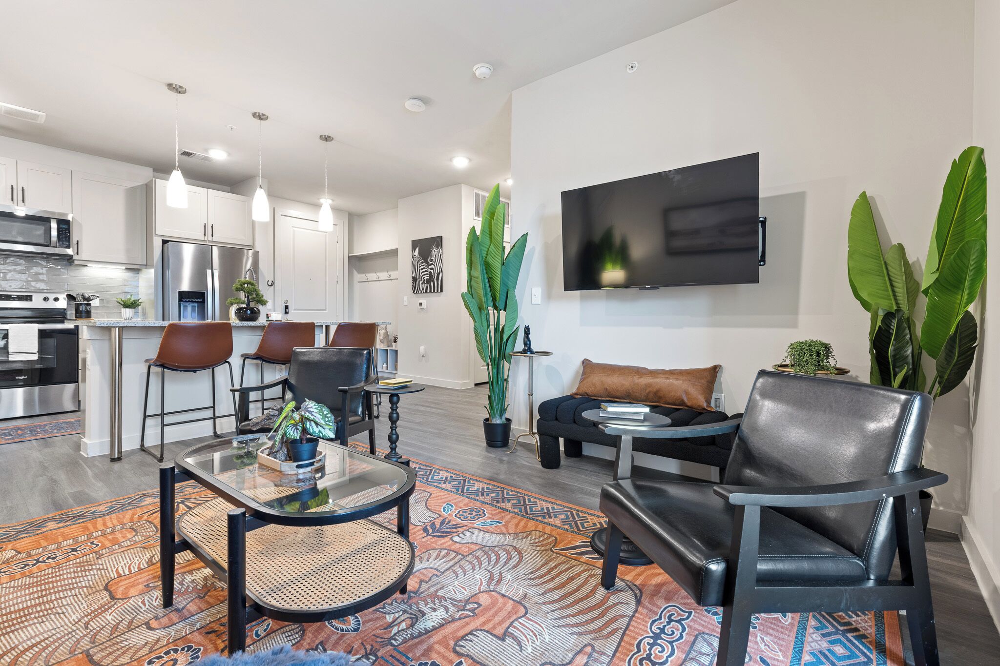 A modern living room with a sofa, chairs, a coffee table, and a TV mounted on the wall.