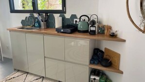 A compact kitchen with a window, a kettle, and various kitchen utensils on the counter. - Relaxation bubble with Jacuzzi (Saint-Martin-de-Londres)
