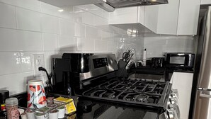 Ett modernt kök med vita skåp, en svart spis och rostfria vitvaror.