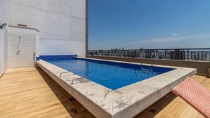 A rooftop pool with a clear blue pool, a wooden deck, and a view of the city skyline. - Ycp704 in S o Paulo (São Paulo)