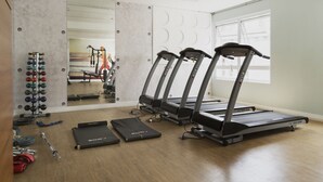 Ein Fitnessstudio mit Laufbändern, Gewichten und einem Spiegel.