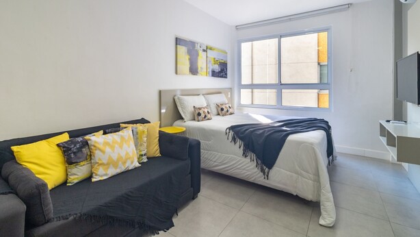 Ein modernes Schlafzimmer mit Bett, Sofa und Fernseher.